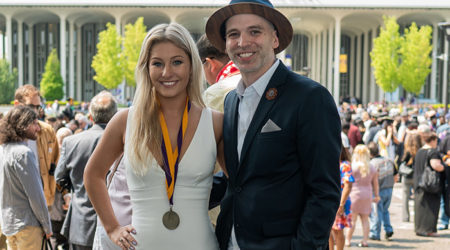 A man and woman posing at UAlbany's graduation ceremony